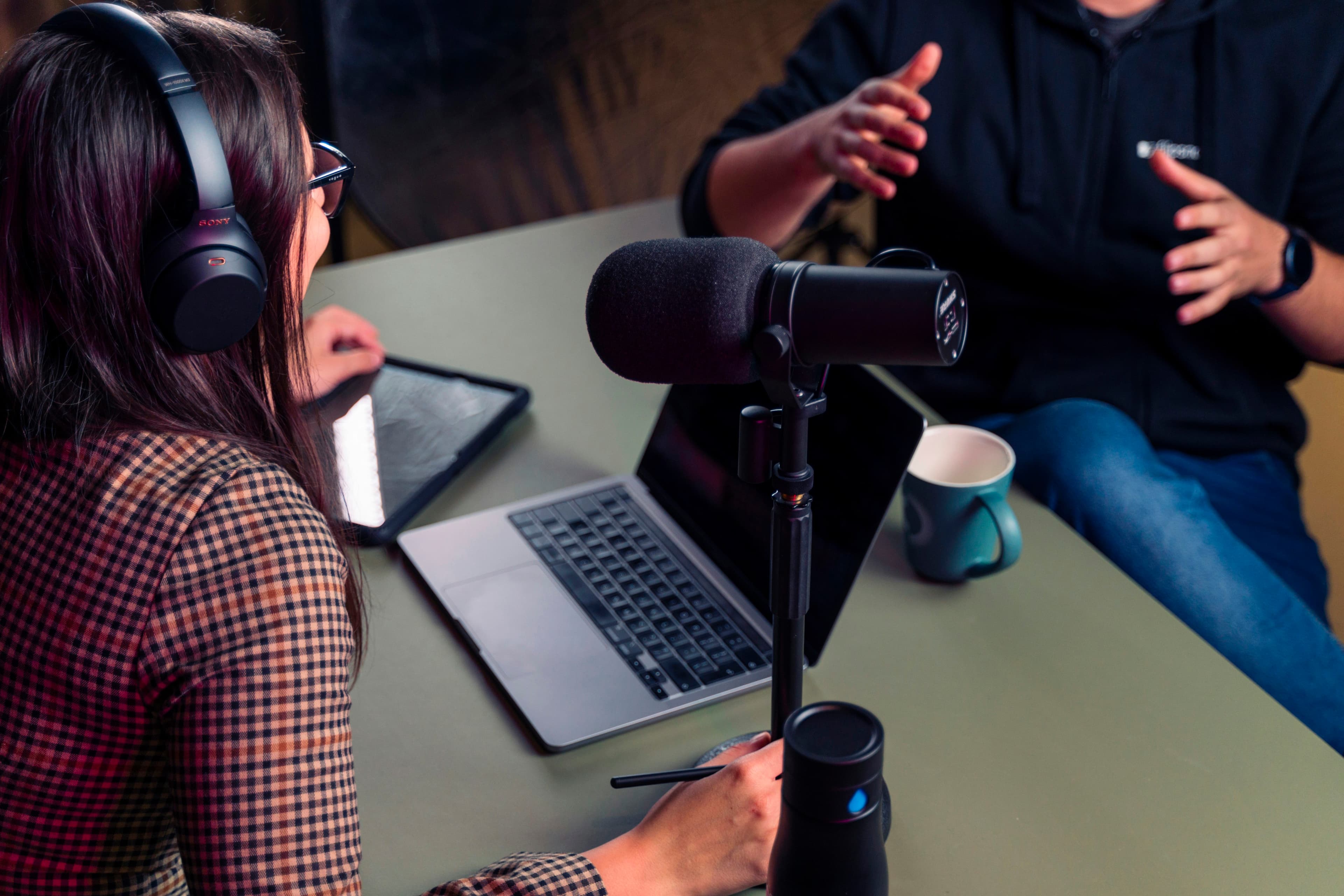 A person wearing headphones watching a video lesson on a laptop, following along with German learning content