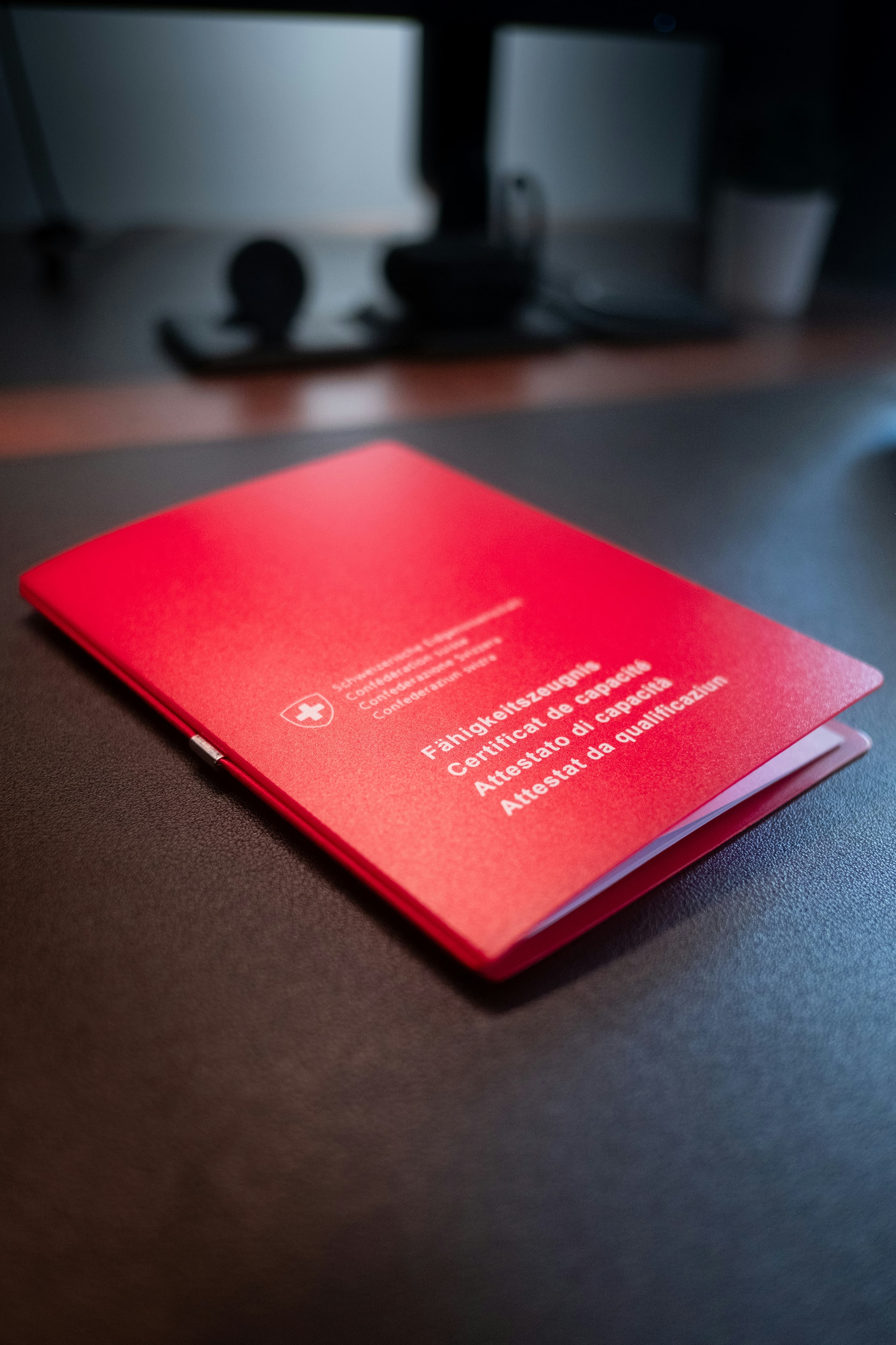 A red certificate of language competence lying on a dark desk