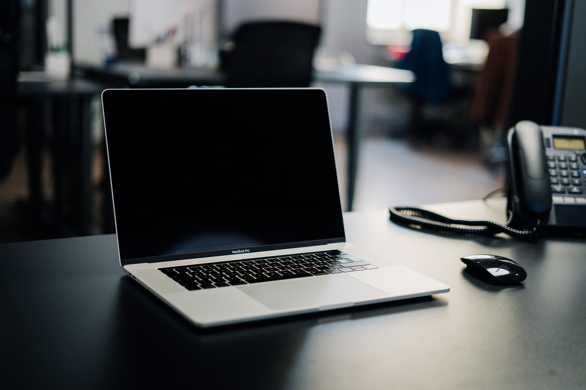 An open laptop on a dark office desk, screen off, ready for the kind of one-on-one online video lesson you'd book on italki or Lingoda